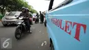 Pengemudi motor melintas di samping mikrolet M 44 yang berderet menutupi persimpangan jalan layang KH Abdulah Syafei, Jakarta, Rabu (25/5). Aksi ini sempat membuat kemacetan panjang menuju Kampung Melayu. (Liputan6.com/Helmi Fithriansyah)