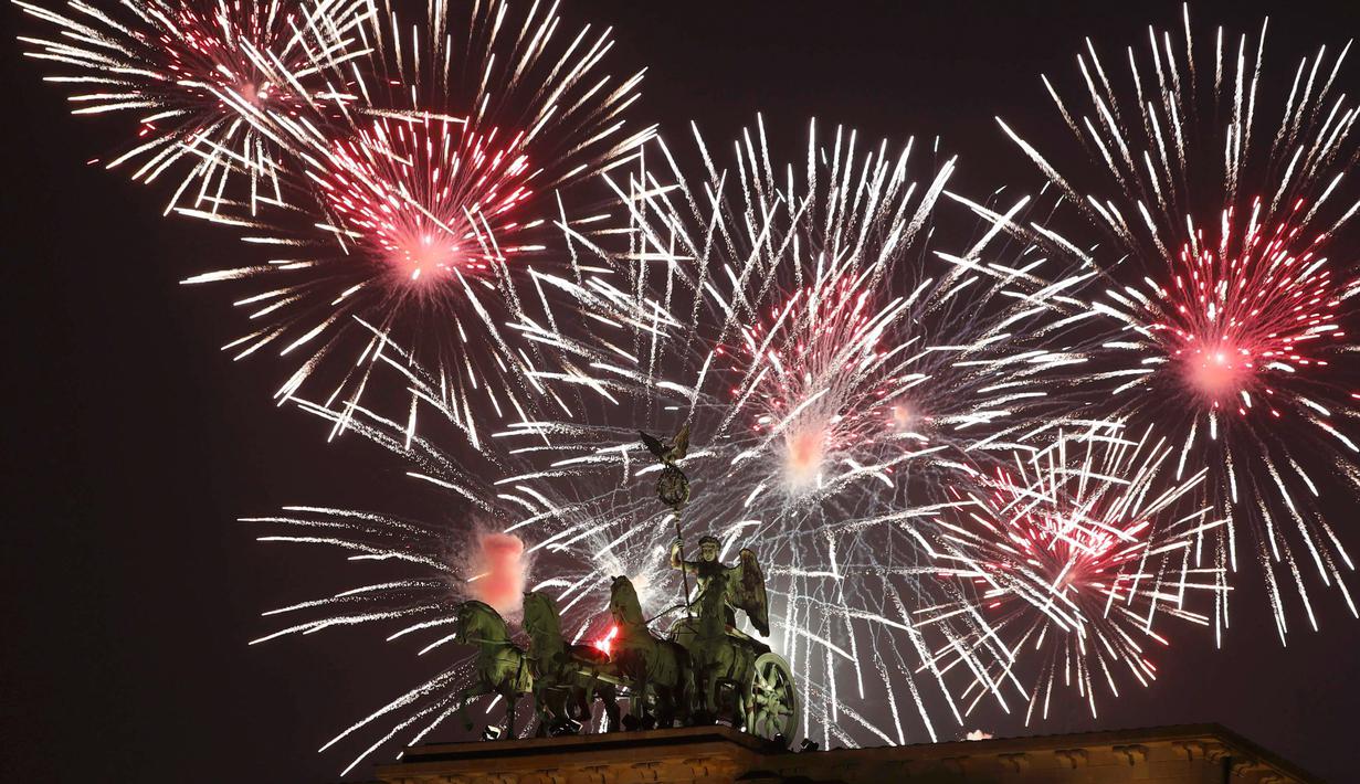Kembang api menghiasi patung Quadriga di pintu masuk Brandenburg pada malam pergantian tahun di Berlin, Jerman, Minggu (1/1). Sebagian besar negara merayakan datangnya tahun baru 2017 dengan pesta kembang api. (REUTERS/Fabrizio Bensch)