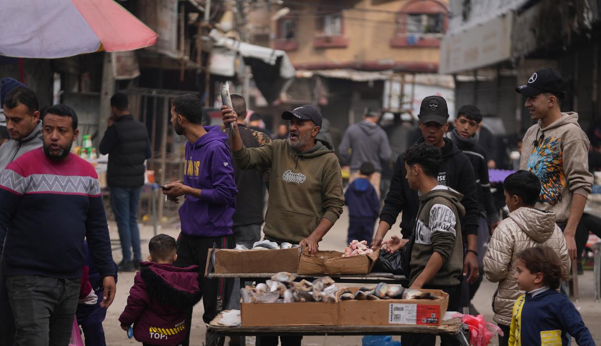 Seorang pedagang Palestina memajang ikan sarden untuk dijual di jalanan pasar lokal di Kota Gaza, Jumat, 19 Desember 2025. Meski kondisi dan situasi masih sangat rapuh akibat kehancuran infrastruktur yang masif akibat serangan Israel sejak Oktober 2023 lalu, dinamika ekonomi di Gaza mulai kembali menggeliat. (AP Photo/Abdel Kareem Hana)