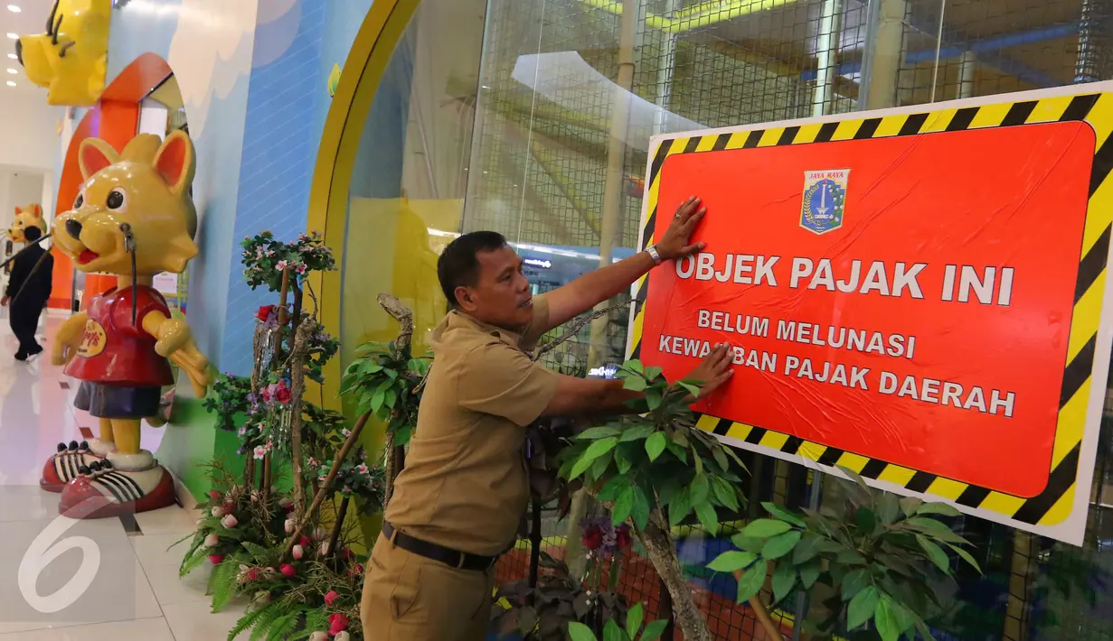 Petugas Dinas Pelayanan Pajak DKI menempel stiker penunggak pajak di wahana bermain anak di pusat perbelanjaan di Senayan, Jakarta, Senin (5/9). Pemasangan stiker dilakukan lantaran wajib pajak tempat usaha itu menunggak pajak. (Liputan6.com/Angga Yuniar)