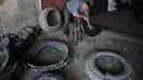 Pria Palestina Mohammed Al-Skafi mengolah sebuah ban kendaraan bekas untuk membuat ember di bengkel kerjanya di Kota Hebron, Tepi Barat (10/11/2020). Al-Skafi menekuni pekerjaan ini dari ayahnya sejak 40 tahun lalu dan dia menggambarkannya sebagai karier yang ramah lingkungan. (Xinhua/Mamoun Wazwaz)