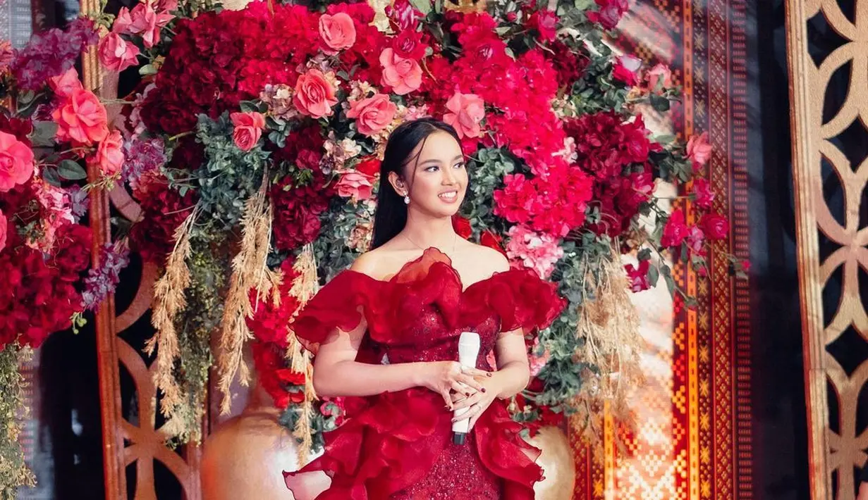 Off shoulder peplum dress berwarna merah ini tampak sangat cantik dikenakan Lyodra. Dress ini memiliki detail ruffle di baagin dada dan pinggang, sedangkan kainnya sendiri dipenuhi payet yang menambah kesan mewah. Foto: Instagram.
