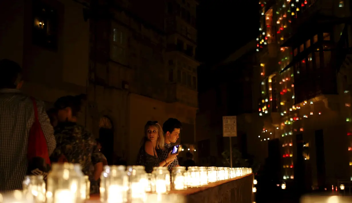 Sejumlah wisatawan menikmati keindahan lilin - lilin saat digelarnya festival Birgu di Malta, Sabtu (10/10/2015). Selama berlangsungnya festival, tidak diperbolehkan menyalakan lampu dan hanya diterangi oleh berbagai jenis lilin. (REUTERS/Darrin Zammit) 	