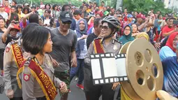 Sejumlah Polisi membawa replika rol film di Bundara HI, Jakarta, Minggu (16/4). Festival film pendek dan film animasi tentang Kepolisian bertajuk Police Movie Festival digelar dengan tema Unity and diversity. (Liputan6.com/Angga Yuniar)