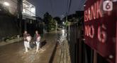 Warga melewati rumah yang tergenang banjir di jalan Bank, Jakarta Selatan, Selasa (4/10/2022). Hujan yang mengguyur wilayah Ibu Kota Jakarta mengakibatkan banjir menggenangi kawasan Kemang, Jakarta. (Liputan6.com/Johan Tallo)