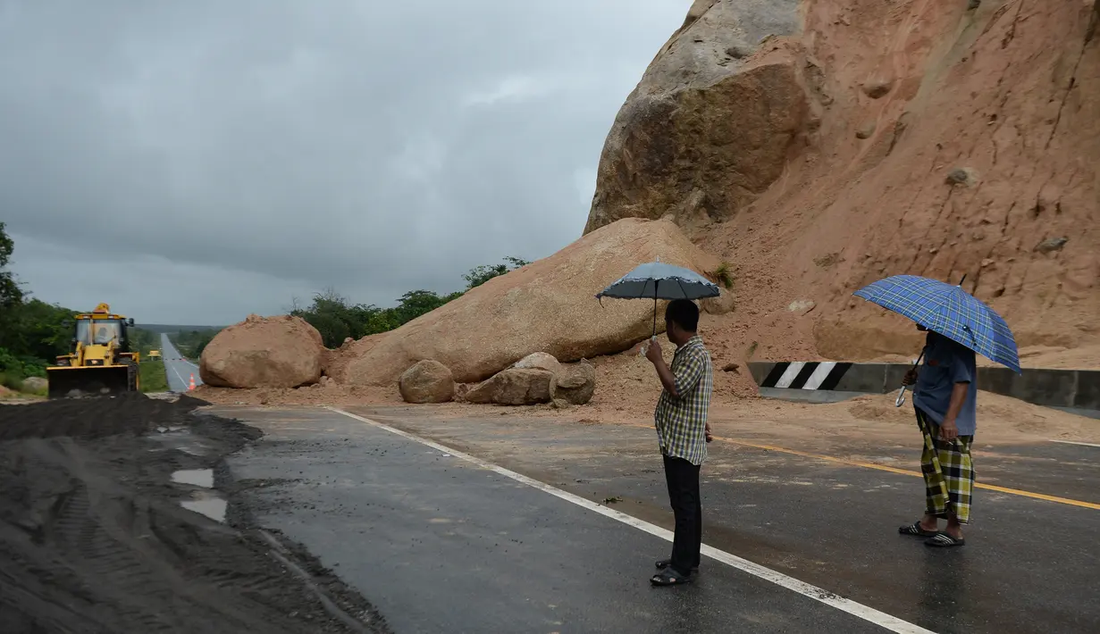Orang-orang melihat batu-batu besar di jalan raya menuju bandara Narathiwat menyusul tanah longsor setelah hujan lebat di Thailand selatan (25/11/2019). Wilayah selatan Thailand akan memasuki musim hujan lebat tiga bulan dari November hingga Januari. (AFP/Madaree Tohlala)