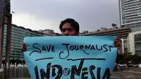Seorang wartawan membentangkan poster saat aksi solidaritas tolak kekerasan terhadap jurnalis di Bundaran HI, Jakarta, Jumat (14/11/2014). (Liputan6.com/Johan Tallo)