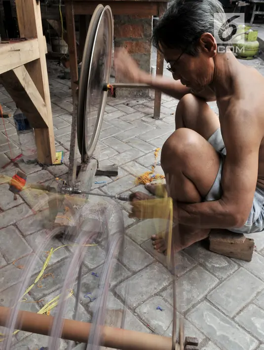 Pengrajin memintal benang saat menyelesaikan pembuatan tenun ikat di salah satu industri rumahan di Desa Bandar Kidul, Kediri, Jawa Timur, Sabtu (29/9). Saat ini banyak pengrajin tenun ikat Bandar Kidul terpaksa gulung tikar. (Merdeka.com/Iqbal Nugroho)