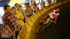 Cagub DKI Jakarta, Basuki T Purnama menyaksikan atraksi Tong Setan saat acara "Bersyukur Jakarta", Jumat (20/1). Dalam acara yang berbentuk bakti sosial dan pasar murah tersebut, terdapat hiburan dan permainan anak. (Liputan6.com/Immanuel Antonius)