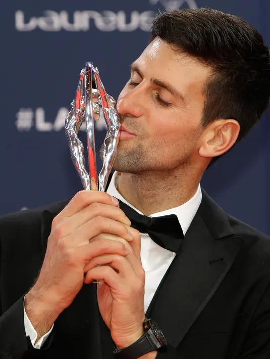 Petenis Serbia, Novak Djokovic mencium trofi seusai meraih penghargaan World Sportsman of the Year dalam ajang Laureus World Sports Awards 2019 di Monako, Senin (18/2). Ini merupakan penghargaan Laureus ke-4 bagi Djokovic. (AP/Claude Paris)