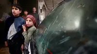 Dua orang anak laki-laki berdiri memperhatikan daerah sekitarnya yang rusak akibat serangan udara di kawasan Douma yang dikuasai para pemberontak di Damaskus, Suriah (7/11). Serangan ini memakan korban yang kebanyakan anak-anak. (Reuters/Bassam Khabieh)