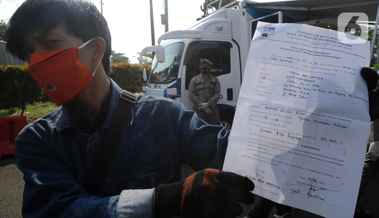 Warga menunjukkan berkas denda saat Operasi Masker Gabungan di Perempatan Ciawi, Bogor, Kamis (10/9/2020). Razia masker yang dilakukan Pemkot dan Pemkab Bogor ini menyasar warga yang tidak mengenakan masker dengan denda sebesar Rp 100.000. (merdeka.com/Arie Basuki)