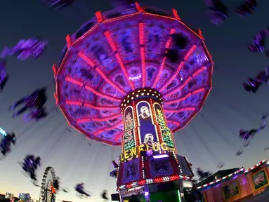 Pengunjung menikmati wahana ayunan ontang-anting saat berlangsungnya festival bir Oktoberfest di Munich, 27 September 2018. Oktoberfest adalah rangkaian festival terbesar di dunia yang diadakan setiap tahun oleh masyarakat Jerman. (AP/Matthias Schrader)
