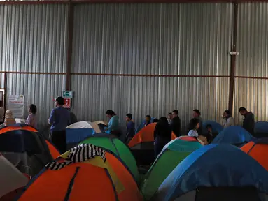 Imigran mengantre makanan di dalam tempat penampungan di Tijuana, Meksiko 6 April 2019. Rombongan migran Amerika Tengah mencapai kota perbatasan antara Meksiko dan AS tersebut  untuk mencari suaka akibat kekerasan, pembunuhan dan kemiskinan yang mengancam