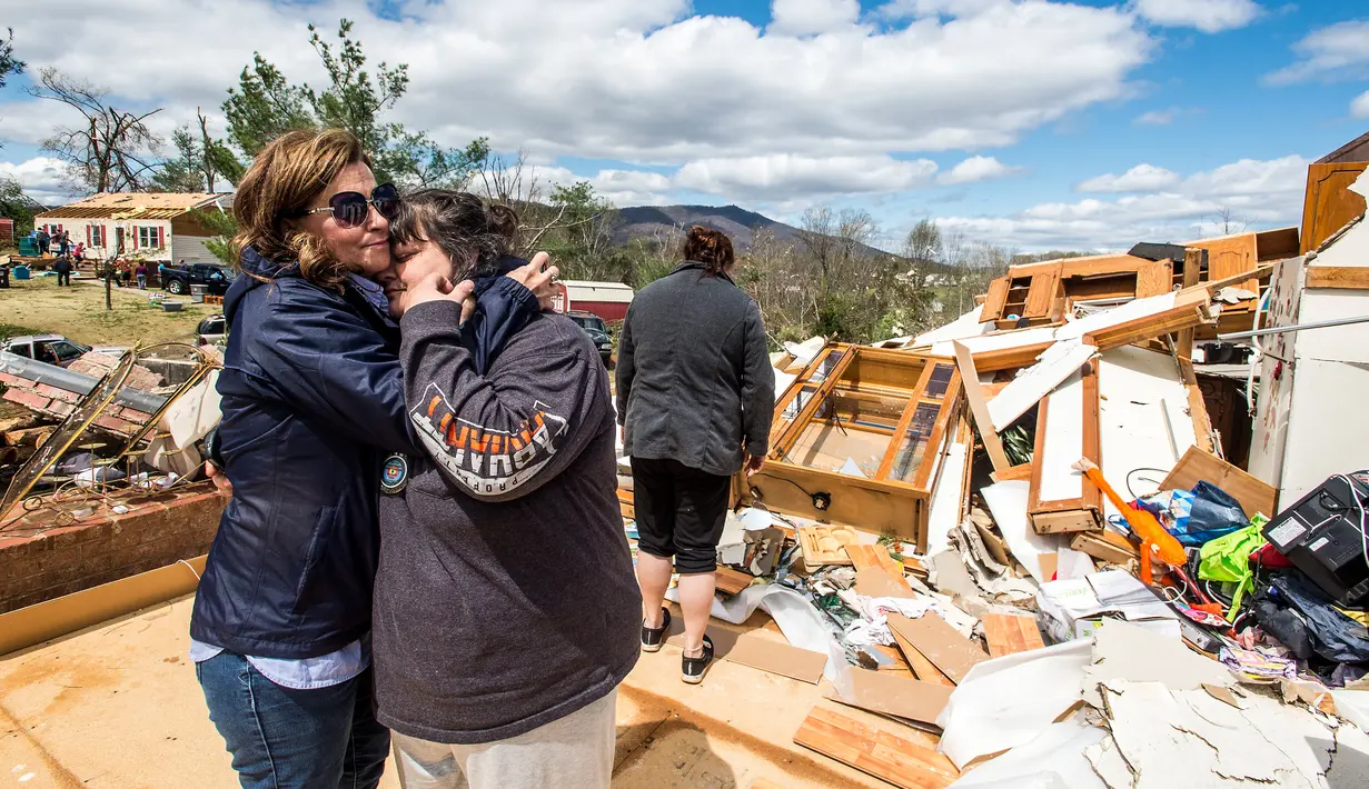 Seorang wanita memeluk keluarganya saat berada di puing-puing rumah mereka yang rusak usai diterjang badai di Elon, Virginia (16/4). Akibat badai ini sejumlah rumah rusak berat. (Jay Westcott/The News & Advance via AP)