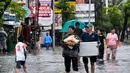 Banjir yang melanda Denpasar terjadi akibat meluapnya saluran drainase yang tidak mampu menampung debit air hujan. Tampak dalam foto, para tamu hotel membawa koper mereka sambil menerobos air di jalan yang tergenang banjir akibat hujan lebat di Legian Kuta, Denpasar, Bali, pada Selasa 24 Februari 2026. (SONNY TUMBELAKA/AFP)