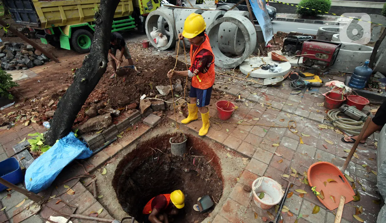Pekerja saat membuat lubang untuk sumur rasapan di Jalan Kebon Jeruk, Jakarta Barat, Jumat (15/10/2021). Pemda DKI Jakarta menargetkan pembuatan 22.292 titik sumur resapan atau drainase vertikal sebelum memasuki puncak musim penghujan pada awal Januari.  (Liputan6.com/Johan Tallo)