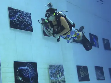 Penyelam melihat pameran foto yang dipamerkan dalam air di Inner Space Club, Beijing, China, Kamis (5/11). 40 karya foto bawah laut dipamerkan untuk memberikan pengalaman menyaksikan pameran foto yang tidak biasa kepada pengunjung (REUTERS/Kim Kyung-Hoon)