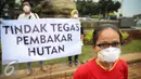 Seorang aktivis mengunakan masker saat aksi solidaritas #melawanasap di Patung Kuda kawasan Merdeka Barat, Jakarta, Jumat (9/10/2015). Aksi mendesak pemerintah beri pelayanan maksimal kepada seluruh korban kebakaran hutan. (Liputan6.com/Faizal Fanani)
