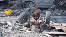 Seorang anak laki-laki Palestina duduk di reruntuhan bangunannya yang hancur akibat serangan udara Israel di Kamp Nuseirat, Jalur Gaza, Palestina, 16 Oktober 2023. (AP Photo/Hatem Moussa)