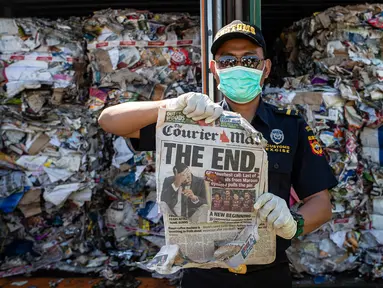 Petugas Bea Cukai Tanjung Perak menunjukkan koran dari kontainer berisi sampah asal Australia di Pelabuhan Tanjung Perak, Surabaya, Jawa Timur, Selasa (9/7/2019). Kantor Bea Cukai Tanjung Perak menindak barang impor berupa delapan kontainer sampah kertas asal Australia. (JUNI KRISWANTO/AFP)