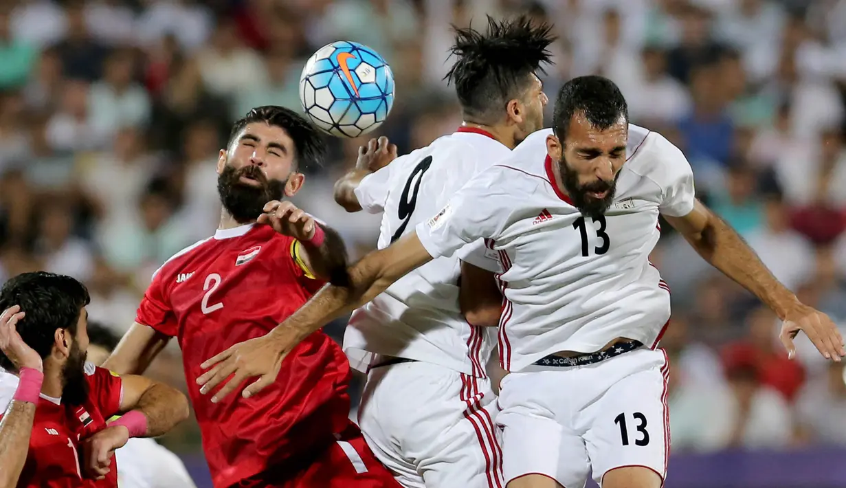 Bek Suriah, Moualad al-Ajjan, duel udara dengan pemain Iran pada laga kualifikasi Piala Dunia 2018 di Stadion Azadi, Taheran, Selasa (5/9/2017). Finis urutan tiga grup A, Suriah lolos ke babak playoff untuk menantang Australia. (AFP/Atta Kenare)