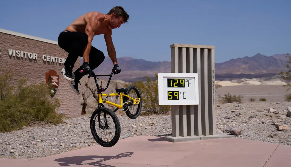 Michael Major mengendarai sepedanya di depan termometer di Pos Pusat Pengunjung Furnace Creek, Taman Nasional Death Valley, California, Senin (17/8/2020). Temperatur udara tertinggi di Dunia -- 54,4 derajat Celcius -- tercatat di Taman Nasional Death Valley. (AP Photo/John Locher)