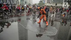 Petugas Penanganan Prasaran dan Sarana Umum (PPSU) membersihkan genangan air saat car free day (CFD) di kawasan Bundaran HI, Jakarta, Minggu (29/12/2019). Pembersihan genangan air dilakukan agar warga yang sedang berolahraga di kawasan tersebut nyaman. (Liputan6.com/Faizal Fanani)
