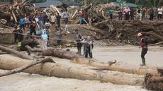 Warga yang menjadi korban banjir bandang di Batang Toru, Tapanuli Selatan, Sumatra Utara menggunakan kayu gelondongan untuk menyeberangi sungai, Selasa 2 Desember 2025. Warga Batang Toru, Tapanuli Selatan, terpaksa menggunakan jembatan darurat yang terbuat dari gelondongan kayu untuk menyeberangi sungai setelah jembatan utama rusak akibat terjangan banjir bandang baru-baru ini. (AP Photo/Binsar Bakkara)