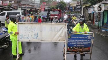 Petugas kepolisian melakukan penutupan jalan KH Hasyim Ashari, Kota Tangerang, Banten, Sabtu (16/7/2022). Intensitas curah hujan yang tinggi sejak Jumat (15/7) siang menyebabkan akses jalan Hasyim Ashari terputus karena terendam banjir setinggi 50 hingga 70 sentimeter. (Liputan6.com/Angga Yuniar)