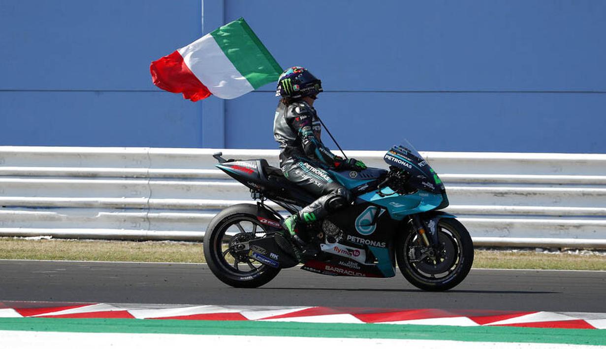 Pembalap Petronas Yamaha, Franco Morbidelli, melakukan selebrasi dengan mengibarkan bendera Italia usai menjuarai MotoGP San Marino di Sirkuit Misano, Minggu (13/9/2020). Morbidelli menjadi yang tercepat dengan catatan waktu 42 menit 02,272 detik. (AP/Antonio Calanni)