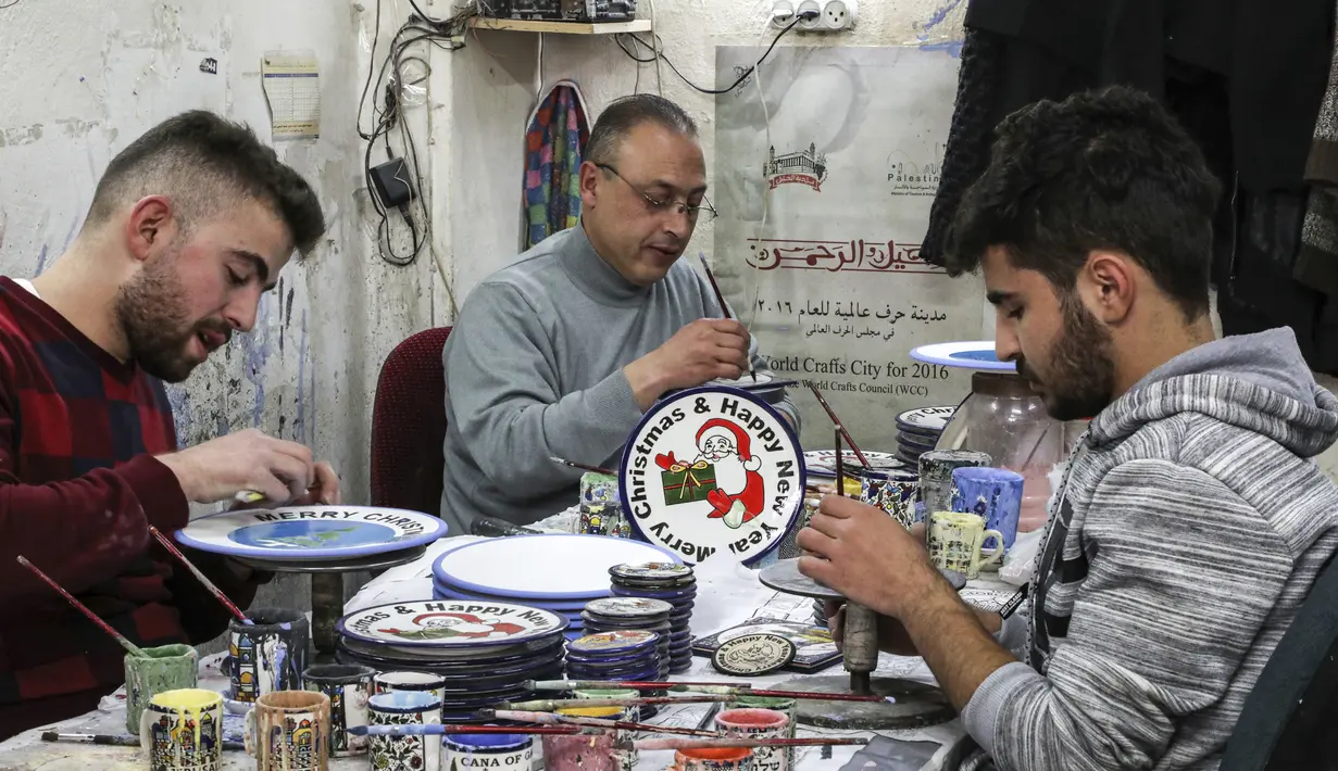 Sejumlah pekerja Palestina menyelesaikan pembuatan piring keramik bergambar hiasan bertema Natal di sebuah pabrik keramik di kota titik nyala Hebron di Tepi Barat (17/12/2019). (AFP/Hazem Bader)