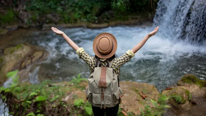 Seorang perempuan sedang menikmati keindahan alam air terjun (Foto Dok: Freepik/freepik)