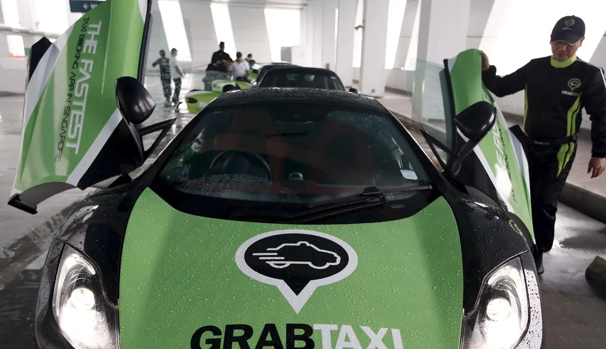 Seorang pengemudi GrabTaxi memeriksa taksi McLaren usai pemotretan dengan tujuh mobil mewah sebelum beroperasi di Singapura, Selasa (15/9). Mobil-mobil mewah itu akan melayani penumpang secara gratis selama musim balapan F1. (REUTERS/Edgar Su)