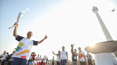 Gubernur DKI Jakarta Anies Baswedan mengangkat obor saat puncak Kirab Obor Asian Games 2018 di Jakarta, Sabtu (18/8). Obor diarak mulai dari Monumen Nasional (Monas) menuju Stadion Utama Gelora Bung Karno (GBK). (Liputan6.com/Faizal Fanani)