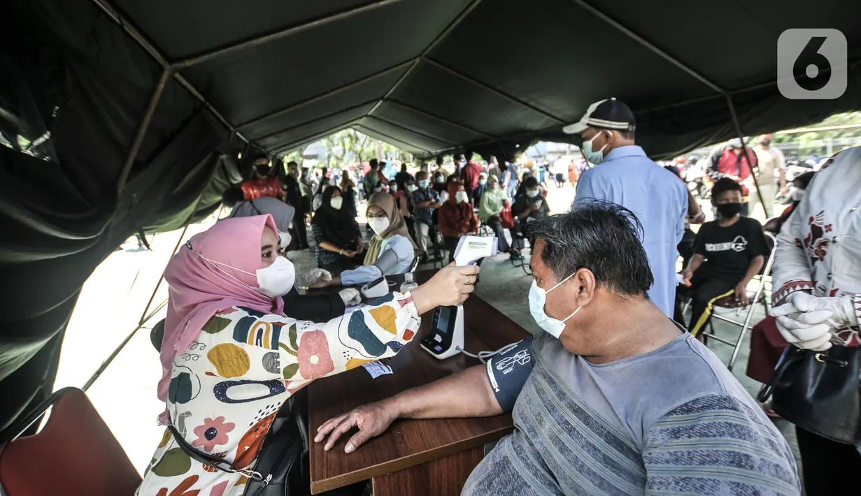 Petugas mengukur suhu warga penerima vaksin Covid-19 saat program Vaksinasi Keliling di RPTRA Pulo Besar, Jakarta, Senin (12/7/2021). Pemprov DKI menggelar Vaksinasi Keliling dengan sistem jemput bola guna mempermudah pelayanan kepada masyarakat di area padat penduduk. (merdeka.com/Iqbal S Nugroho)