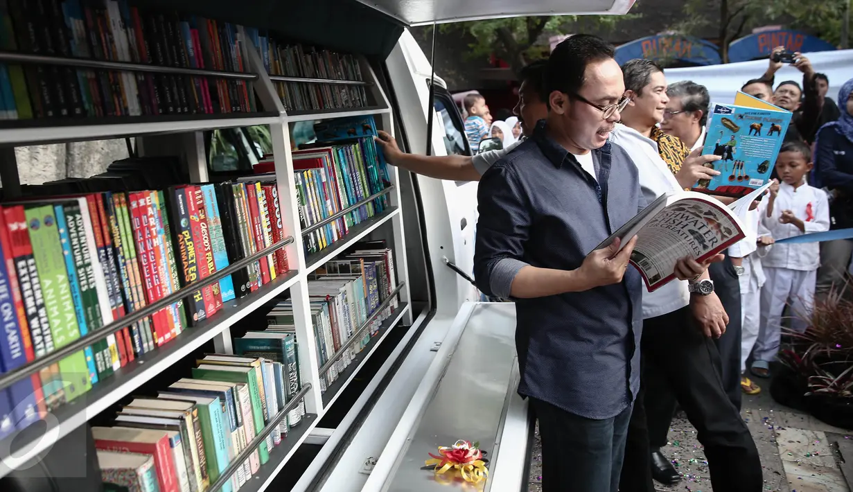 Direktur Utama PJAA Gatot Setyowaluyo membaca buku usai meluncurkan Mobil Pintar Ancol di Ancol, Jakarta, Rabu (15/6/2016). Tujuan program Mobil Pintar Ancol ini untuk meningkatkan minat baca di kalangan anak-anak. (Liputan6.com/Faizal Fanani)