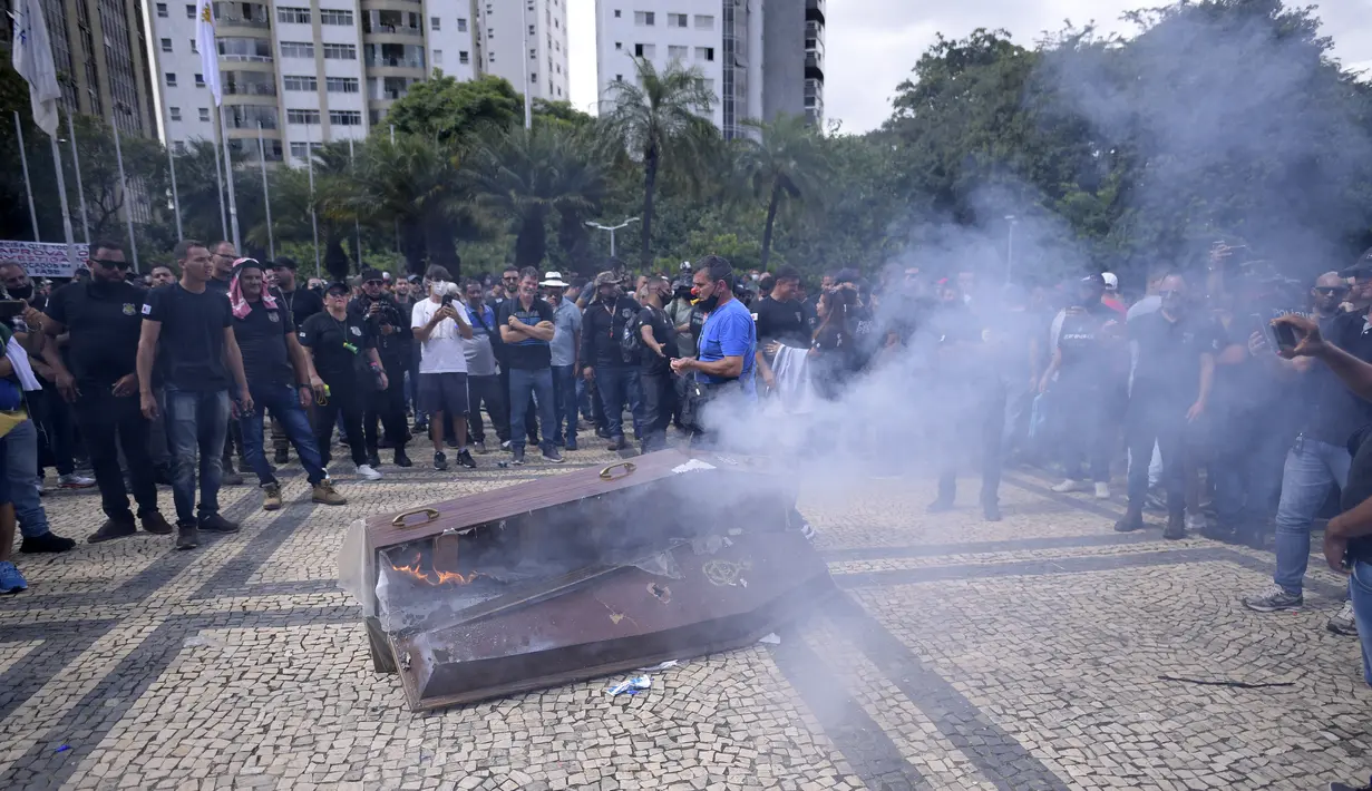 Petugas polisi dan agen pasukan keamanan negara bagian Minas Gerais memprotes dengan peti mati tiruan yang berpura-pura menjadi milik Gubernur Romeu Zema, untuk menuntut gaji yang lebih tinggi di Belo Horizonte, Brasil pada 21 Februari 2022. (Douglas MAGNO/AFP)