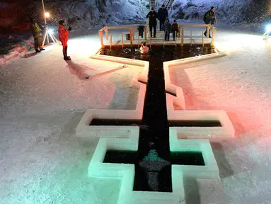 Penganut Kristen Ortodoks terjun ke kolam air es selama perayaan liburan Epiphany di Desa Tyarlevo di luar Saint Petersburg, Rusia, Kamis (18/1). (Olga MALTSEVA/AFP)