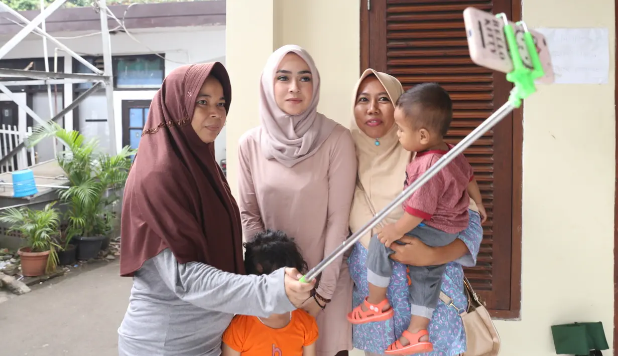 Salah satu hal yang diakukan Aryani saat jeda syuting adalah melayani para penggemar yang datang ke lokasi syuting untuk sekedar berfoto dengan dirinya. Meski lelah, Aryani tetap harus meladeni mereka. (Nurwahyunan/Bintang.com)