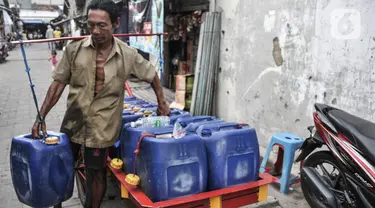 Pedagang mengantarkan air pikulan kepada warga di kampung nelayan Kalibaru, Cilincing, Jakarta Utara, Selasa (22/3/2022). Hingga kini air pikulan masih menjadi kebutuhan utama warga di kawasan pesisir Cilincing untuk keperluan konsumsi akibat air sumur keruh dan bau. (merdeka.com/Iqbal S Nugroho)