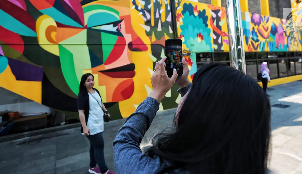 Warga foto di dekat karya seni Mural di Taman Ismail Marzuki (TIM), Cikini, Jakarta, Selasa (11/9). Mural tersebut dibuat oleh seniman asal Kolombia Diana Ordonez. (Liputan6.com/Faizal Fanani)