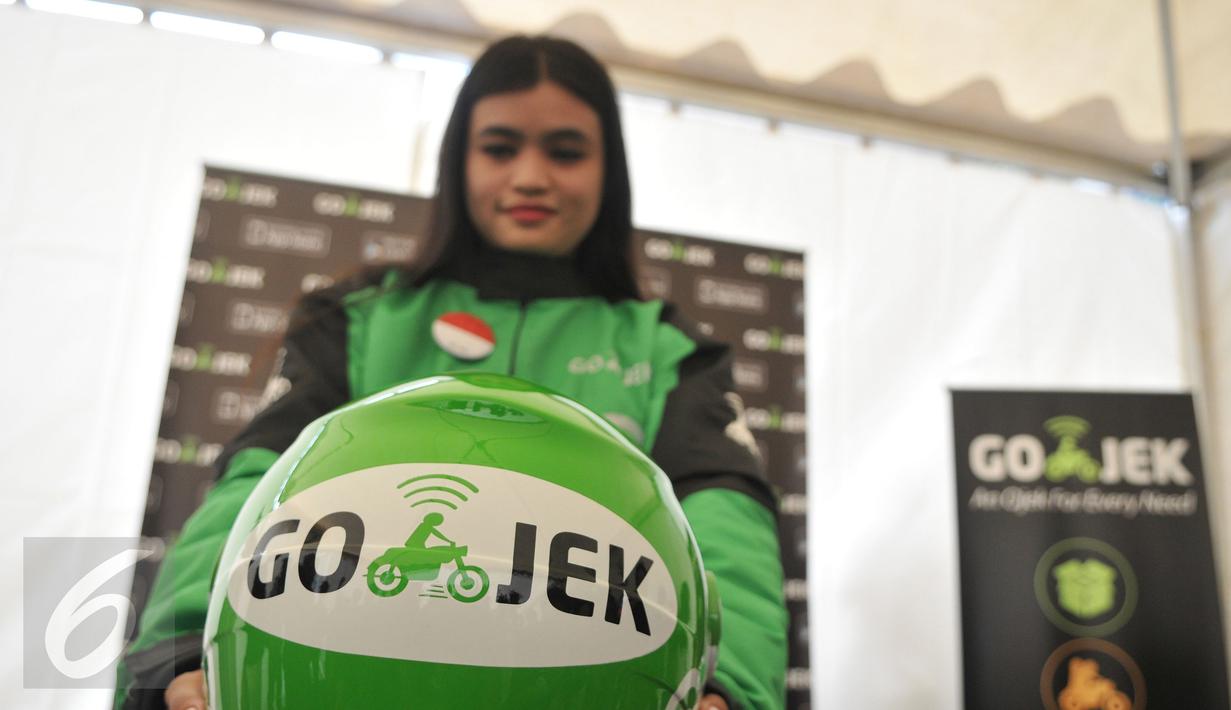 Seorang wanita memamerkan helm yang bertuliskan Go-Jek usai diterima sebagai pengendara Go-Jek di Hall A Basket Senayan, Jakarta, Jumat (14/8/15). Fenomena ojek online dengan aplikasi di hanphone kini banyak diminati. (Liputan6.com/Herman Zakharia)
