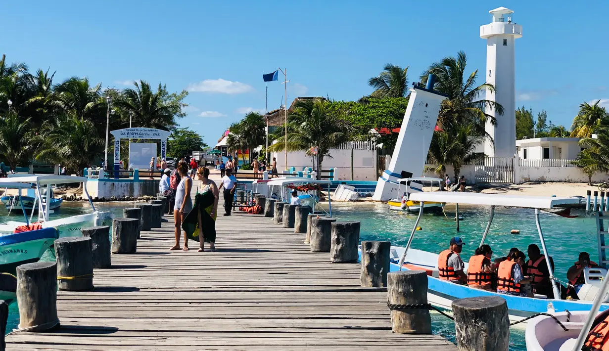 Turis berjalan di sepanjang dermaga di Puerto Morelos, negara bagian Quintana Roo, Meksiko (14/2). Puerto Morelos dibagi oleh jalan raya dan rawa bakau menjadi tiga bagian. (AFP Photo/Daniel Slim)