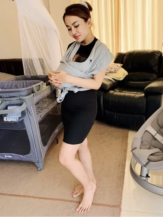 Saat menggendong anak, ia pun memerlihatkam rambut cokelat yang ia kuncir dengan mengenakan dress hitamnya. (@medinazein92)