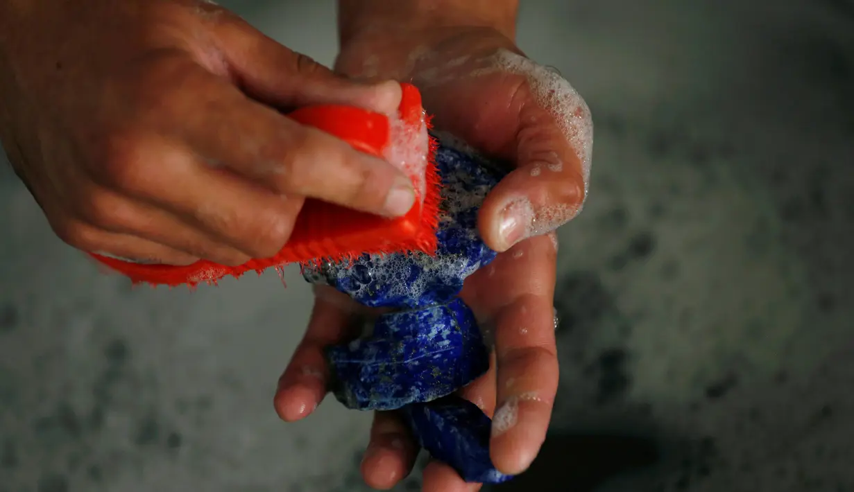  Seorang pria mencuci lapis lazuli di tokonya di Kabul, Afghanistan (5/6/2016). Batu yang dikenal dengan sebutan 'batu surga' ini merupakan batu permata langka yang dihargai sejak zaman kuno karena warna birunya. (REUTERS/Mohammad Ismail)