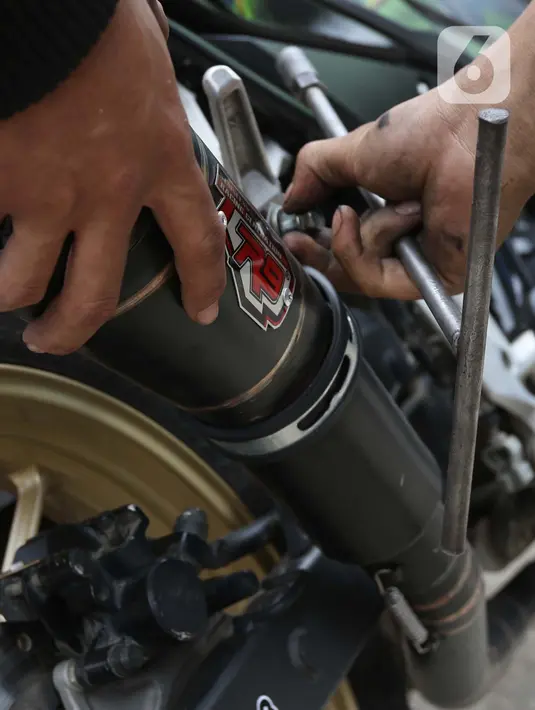 Pengendara motor mencopot knalpot bising usai terjaring razia yang digelar Satlantas PolresMetro Depok di Jalan Margonda Raya, Depok, Kamis (18/3/2021). Puluhan motor berknalpot bising yang terjaring razia diwajibkan mengganti knalpot dan diberi sanksi tilang. (Liputan6.com/Helmi Fithriansyah)