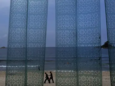 Dua pria terlihat dari tirai plastik sebuah restoran berjalan di pantai Sijung Ho di Korea Utara (14/7/2019). Pantai Sijung Ho merupakan tujuan wisata populer bagi penduduk lokal dan asing. (AP Photo/Vincent Yu)