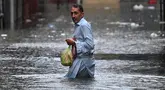 Seorang pria menyeberangi jalan yang tergenang air saat hujan monsun lebat di Rawalpindi, Pakistan, pada 17 Juli 2025. (Aamir Qureshi/AFP)