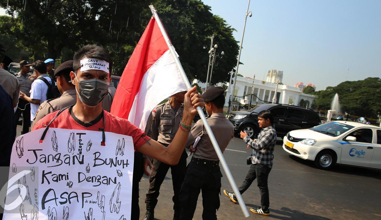 Seorang mahasiswa Riau Jabodetabek membawa bendera merah putih saat unjuk rasa di depan Istana Merdeka, Jakarta, Jumat (18/9/2015). Mereka menuntut penegakan hukum hingga tuntas pelaku pembakaran. (Liputan6.com/Faizal Fanani)
